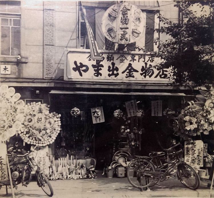 やま出金物店は、現在の京都市下京区大宮七条西入る の北側(現在のみずほ銀行の付近)にありました。梅次郎の好みにより夜中まで煌々とネオンが輝く非常に派手な店構えだったとのことです。